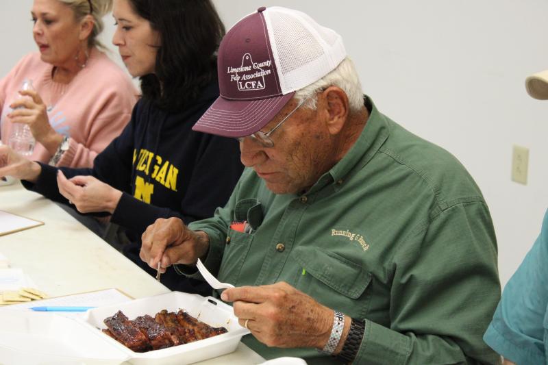 Distinguished local and ribs judge Arnold Gray carefully considers the entry in front of him before cutting off a bite at the ‘Go Texan BBQ Cookoff’ on Saturday, March 16.  Racheal Clark photo/Groesbeck Journal